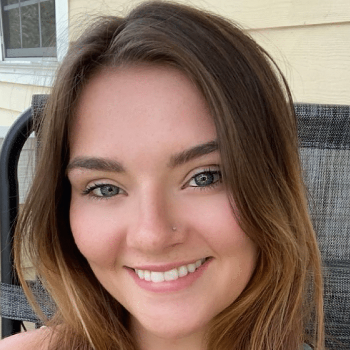 Smiling person sitting outside on a patio chair.